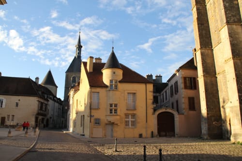 Medieval stone courtyard with yellow chateau and church spires in Sermizelles, France
