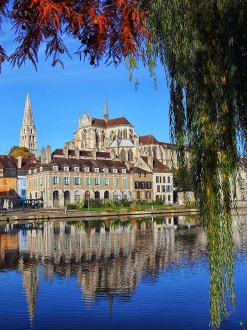 Medieval cathedral and colorful buildings reflecting in calm river waters, Auxerre, France