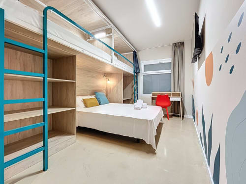 Modern private room at Lemon Hostel Altea with turquoise shelving, bed, desk, red chair, and abstract wall art