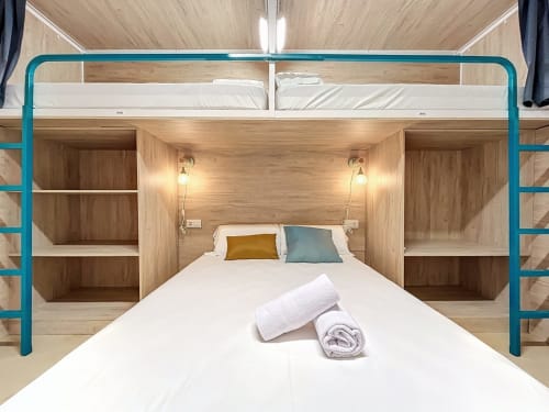 Modern private room at Lemon Hostel Altea with turquoise bunk bed frame, wooden shelving, and welcoming towels.