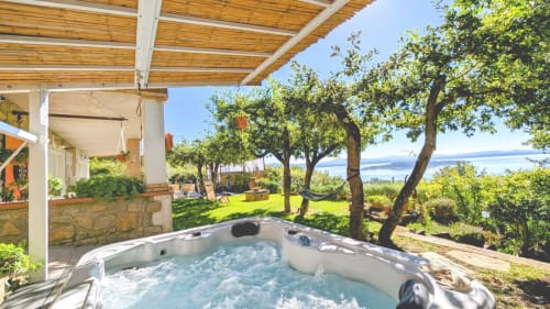 Vasca idromassaggio con vista sul lago e paesaggio italiano, proprietà Villa Italia Management con giardino e alberi