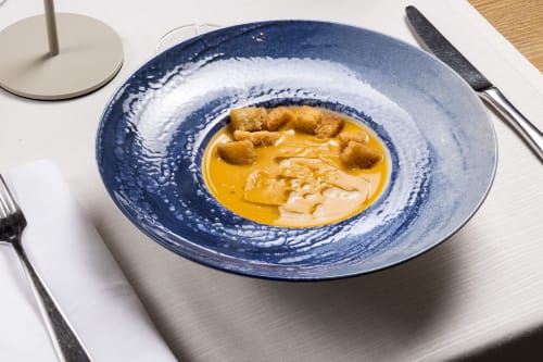 Gourmet seafood soup at Palazzo Belvedere, Chianciano Terme featuring seared scallops in golden broth on blue ceramic plate