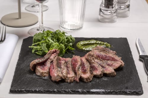 Sliced rare steak with arugula and herb sauce on black slate at Palazzo Belvedere, Chianciano Terme