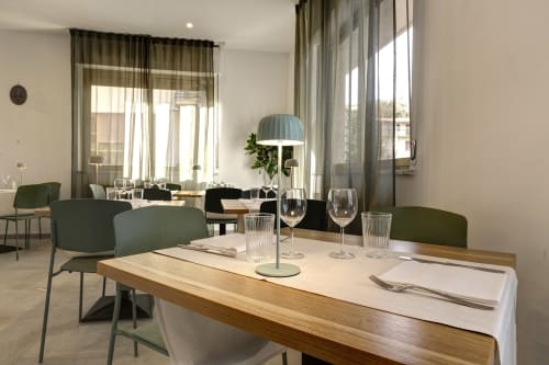 Modern dining room at Palazzo Belvedere hotel in Chianciano Terme with wooden table, green chairs, and city views
