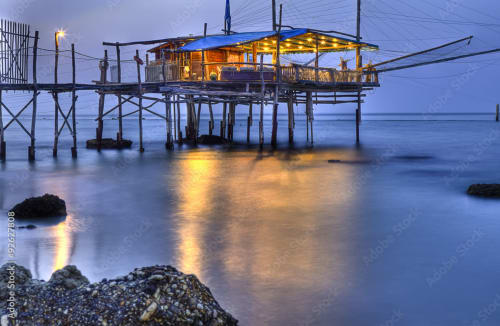 Ristorante illuminato sulla spiaggia su palafitte al tramonto, Tales of Abruzzo, Atessa Italia
