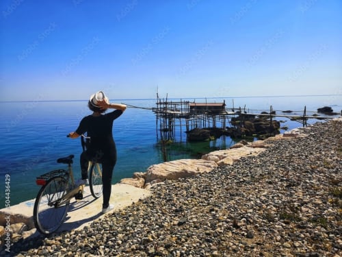 Ciclista con bicicletta che ammira il Mar Adriatico vicino ad Atessa, Italia con tradizionali strutture di pesca