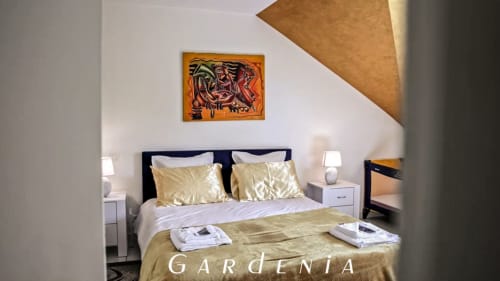 Chambre Gardenia de la Villa Pré d'Oro - lit double aux coussins dorés satinés et tableau expressionniste sous les combles
