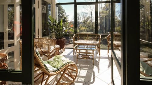 Véranda ensoleillée de la Villa Pré d'Oro avec salon en rotin et vue panoramique sur le jardin