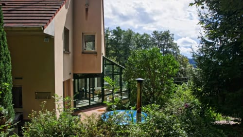 Vue latérale de la Villa Pré d'Oro avec véranda vitrée, jardin luxuriant et piscine privée