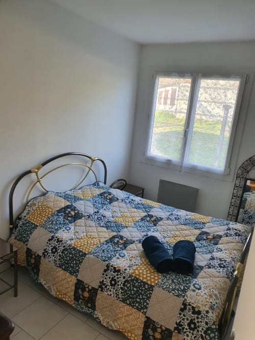 Chambre douillette à l'Hôtel Cheverny La Vie Est Belle avec courtepointe patchwork, lit en métal et vue sur le jardin par les fenêtres