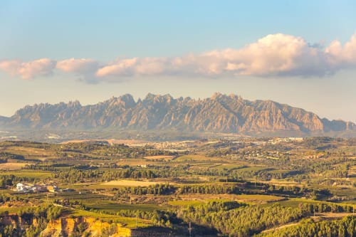 La montaña de Montserrat domina tierras de cultivo exuberantes junto al hotel Masia Can Canyes en Sant Llorenç d'Hortóns, Penedes
