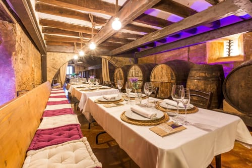 Elegante comedor con barriles de madera en Masia Can Canyes, manteles blancos e iluminación ambiental púrpura. Restaurante gastronómico y bodega 