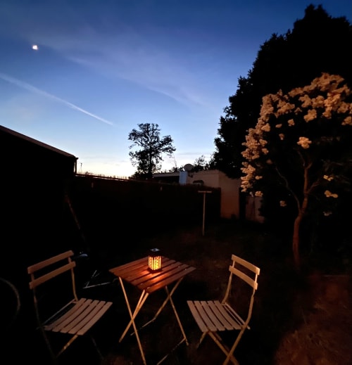 Terrasse du soir du cottage Accolade à Châteaudun avec table éclairée aux chandelles et chaises sous un ciel étoilé