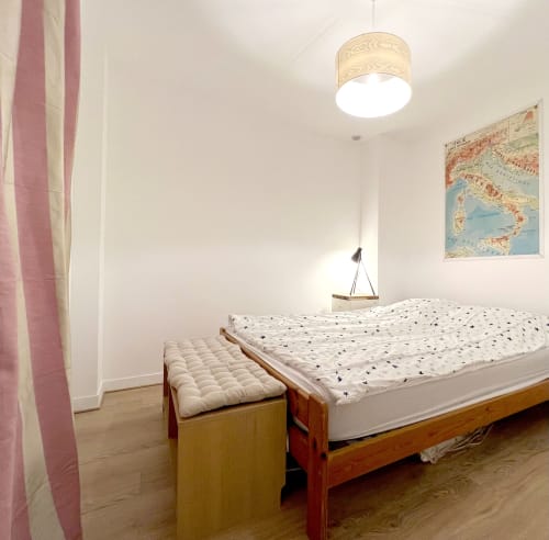 Chambre lumineuse du gîte Accolade à Châteaudun avec lit en bois, rideaux roses et carte vintage d'Italie