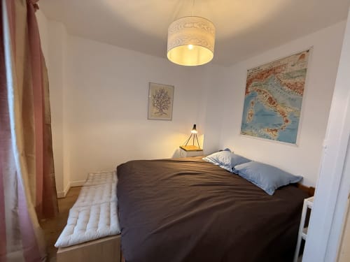 Chambre cosy de cottage à Accolade à Châteaudun : lit foncé, luminaires suspendus, carte d'Italie et décoration nautique