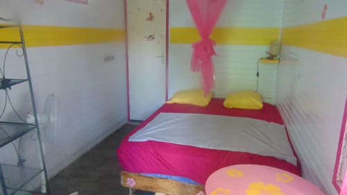 Chambre lumineuse de la villa Caribgites à Sainte-Anne, décoration rose et jaune, lit double et ventilateur
