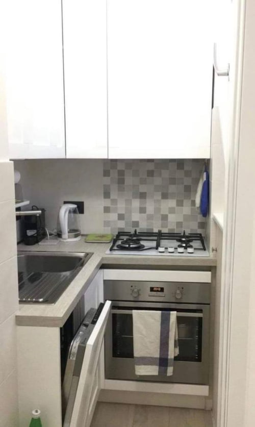 Kompakte Küche in der Magnolia Apartments Mailand mit weißen Schränken, Gasherd, Elektroofen, Spüle und gefliester Rückwand