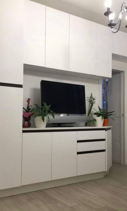 Moderne weiße Küche mit Flachbildfernseher, Topfpflanzen und schwarzer Arbeitsplatte in den Magnolia Apartments Mailand.