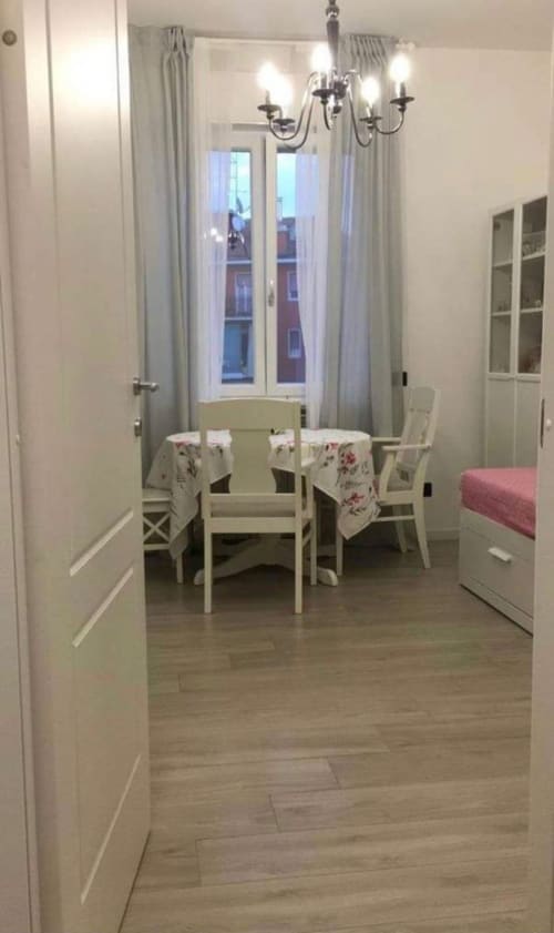 Elegantes Esszimmer in der Magnolia Apartments Mailand mit weißen Möbeln, Kronleuchter, Stadtblick und modernen Annehmlichkeiten