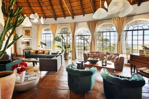 Salon luxueux de la chambre d'hôtes Alombre à Lectoure avec baies cintrées, fauteuils velours vert et carrelage terre cuite