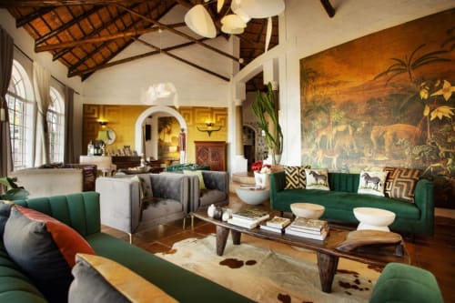 Le salon de l'Alombre B&B à Lectoure offre un mobilier en velours vert, des poutres en bois et une fresque aux motifs safari