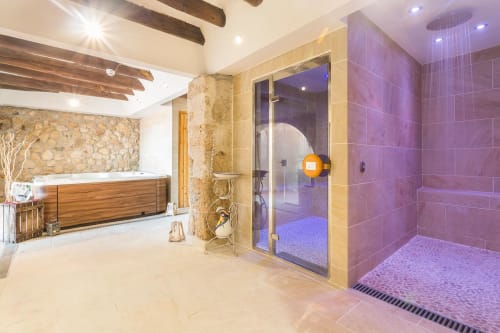Salle de bain spa luxueuse à Masia Can Canyes avec douche hammam, baignoire en bois et murs en pierre à Sant Llorenç d'Hortóns