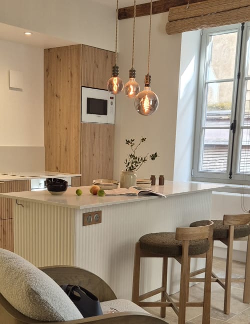 Modern keuken met houten kasten, hangende lampen en bar zitplaatsen in het appartement Moulin Renaudiots in Autun