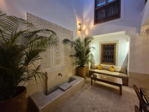 Cour traditionnelle marocaine du Riad Casa Angelo avec zelliges, plantes vertes, fontaine et coin salon intégré