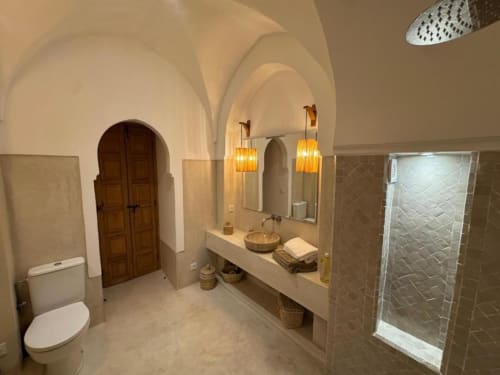 Salle de bain luxueuse dans la Suite Jamal du Riad Casa Angelo, Marrakech avec plafonds voûtés, comptoirs en marbre, luminaires suspendus, et