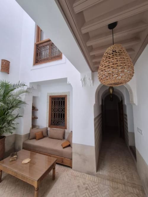 Cour marocaine traditionnelle du Riad Casa Angelo avec lampe suspendue tissée, porte cintrée et sièges rembourrés
