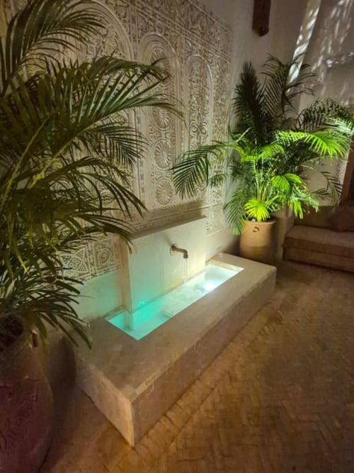 Cour du Riad Casa Angelo avec bassin illuminé, palmiers et zellige ornemental à Marrakech
