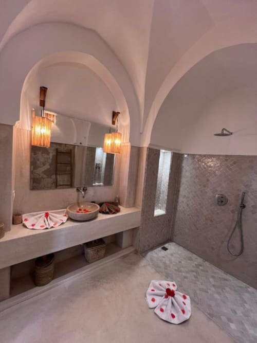 Salle de bains luxueuse de la Suite Jamal au Riad Casa Angelo à Marrakech avec plafonds voûtés, vasque en marbre, éclairage chaleureux et douche