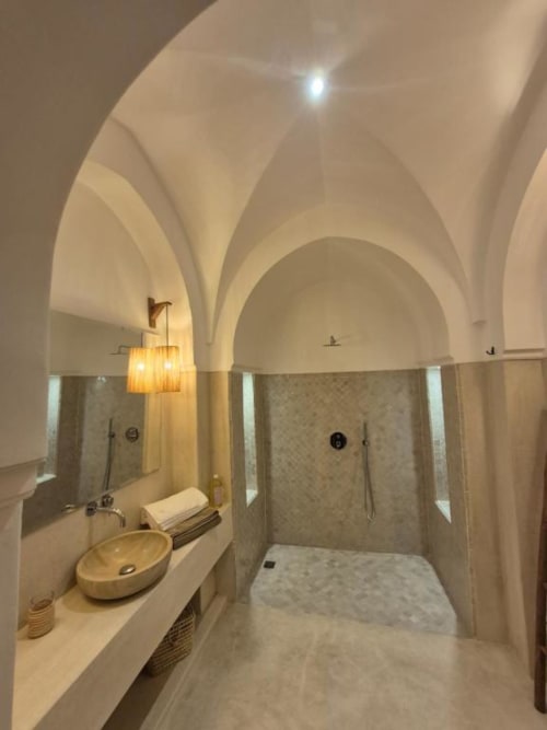 Salle de bains luxueuse de la Suite Jamal au Riad Casa Angelo, Marrakech, avec plafonds voûtés, sols en marbre, vasque et