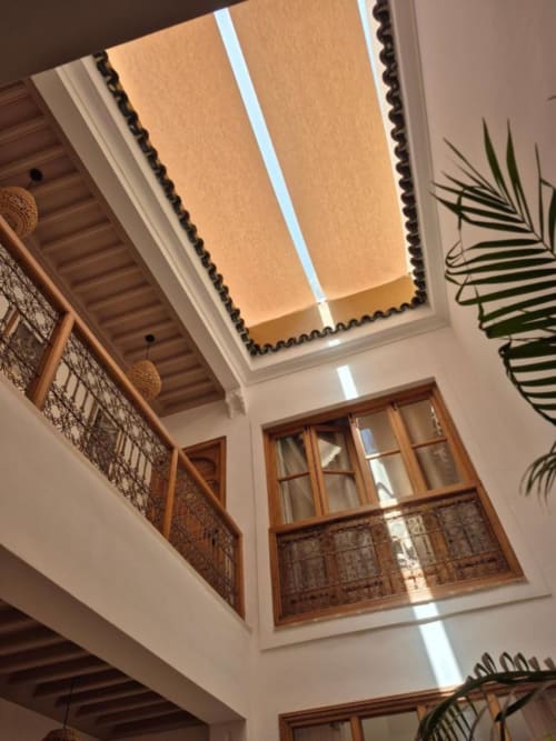 Cour du Riad Casa Angelo à Marrakech avec balustrades en bois, fenêtres en arc et puits de lumière
