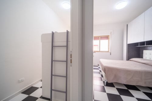 Camera moderna del Marina di Strongoli BnB con pareti bianche, pavimento in piastrelle bianche e nere, letto matrimoniale e finestra con vista mare