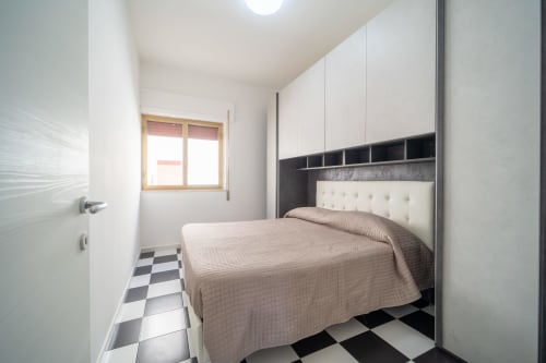 Camera da letto moderna con testata bianca, vista mare, pavimento a scacchi bianco e nero a Marina di Strongoli
