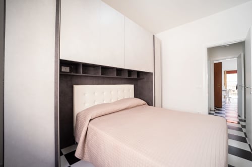 Camera da letto moderna con armadi incassati bianchi, testata trapuntata color crema e biancheria rosa a Marina di Strongoli fronte mare