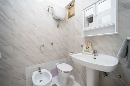 Bagno moderno nell'appartamento di Marina di Strongoli con piastrelle in marmo, lavabo bianco, bidet, wc e mobile a muro