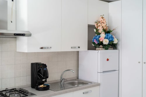 Cucina moderna nell'appartamento fronte mare di Marina di Strongoli con mobili bianchi, lavello in acciaio inox, piano cottura a gas