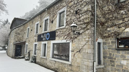 Façade extérieure de l'hôtel Le Moulin Des Ramiers à Crupet, Belgique, avec murs en pierre couverts de lierre et signalétique