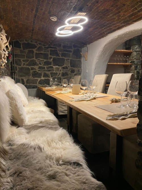Salle à manger élégante du Moulin Des Ramiers avec murs en pierre, table en bois, éclairage néon et sièges moelleux