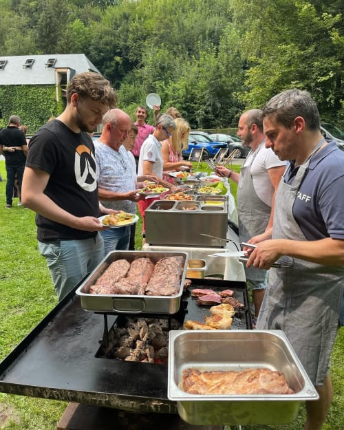 Buffet barbecue en plein air à l'hôtel Le Moulin Des Ramiers de Crupet, clients se servant de viandes grillées aux tables