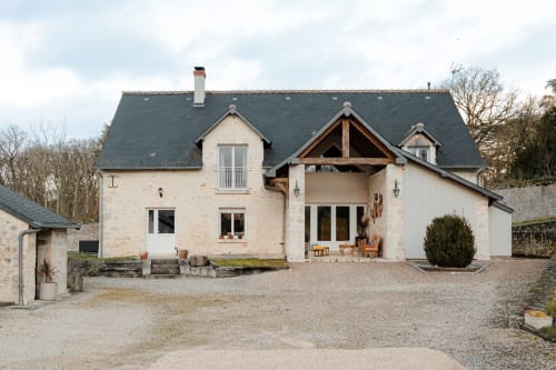 Front view of Le Logis — a peaceful stone house with a wooden porch; the entrance is through the left‑hand door for a relaxing stay near Blois.
