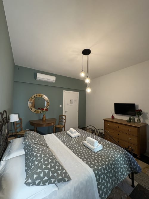 Camera Carmen presso l'hotel Le Arche di Verona con letto, cassettone in legno, specchio decorativo e luci a sospensione