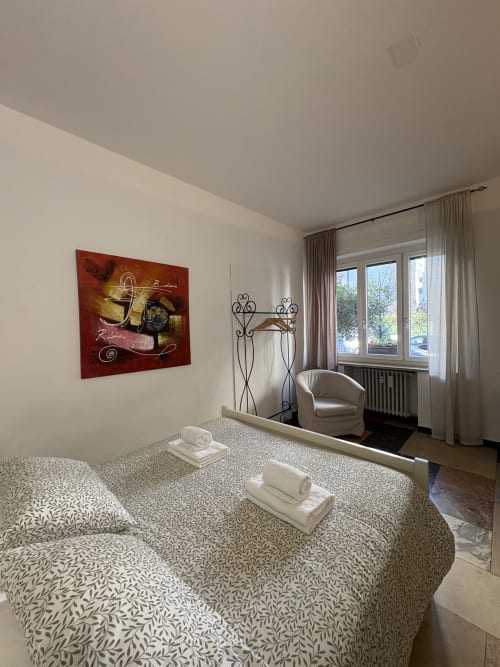 Camera moderna all'hotel Le Arche di Verona con biancheria a motivi, opere d'arte vinicola e vista sulla città