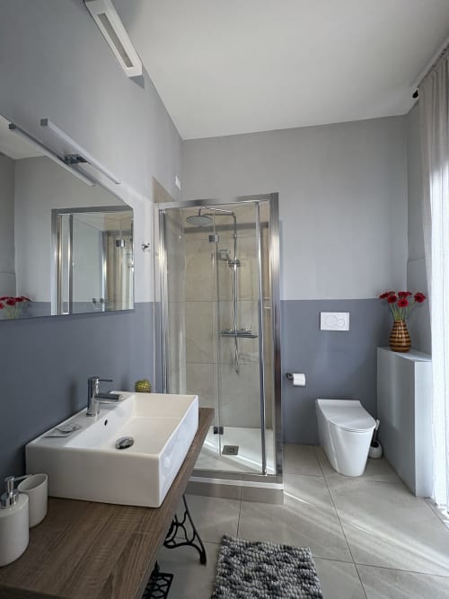 Bagno moderno dell'hotel Le Arche di Verona con doccia, lavabo, WC e rivestimenti in piastrelle grigie