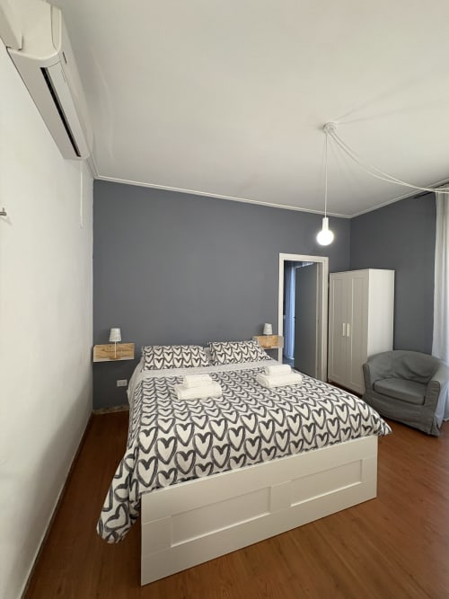 Camera moderna all'hotel Le Arche di Verona con letto matrimoniale, parete in grigio, guardaroba bianco e pavimento in legno