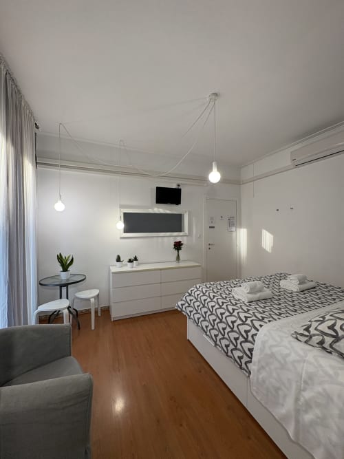 Camera moderna dell'hotel Le Arche a Verona con letto, cassettiera bianca, lampade a sospensione e pavimento in legno