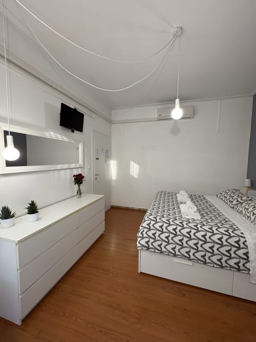 Camera moderna dell'hotel Le Arche a Verona con mobili bianchi, biancheria decorativa e pavimento in legno