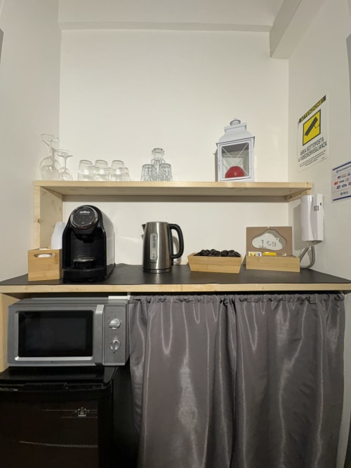 Kitchenette Le Arche Verona con macchina per espresso, bollitore, microonde e scaffali organizzati